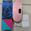 Pink heating pad with packaging, USB cable, and user manual on a tiled floor.